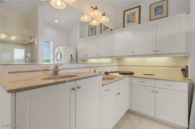 kitchen with light tile patterned flooring, sink, light stone counters, backsplash, and white cabinets