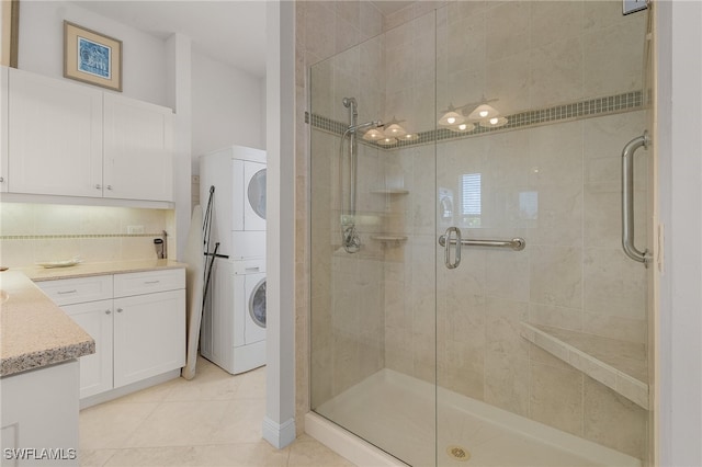 bathroom featuring a shower with door, stacked washer and clothes dryer, tile patterned flooring, tasteful backsplash, and vanity