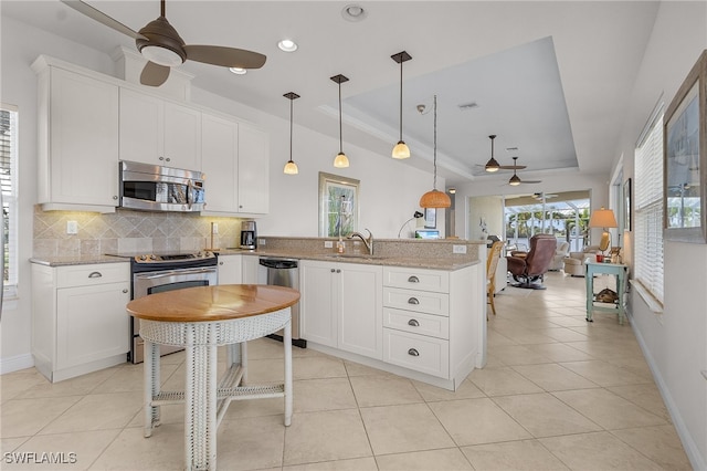 kitchen with stainless steel appliances, light stone counters, and a raised ceiling