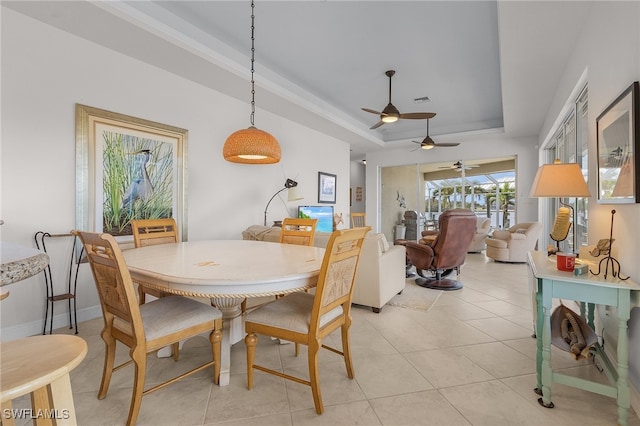 tiled dining space featuring ceiling fan and a raised ceiling