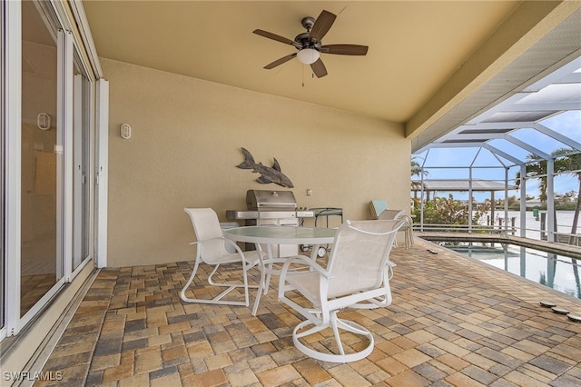 view of patio featuring glass enclosure, a water view, and ceiling fan