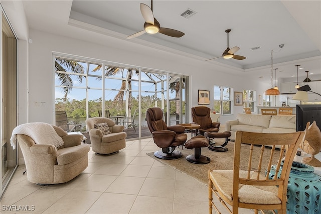 tiled living room with a tray ceiling and ceiling fan