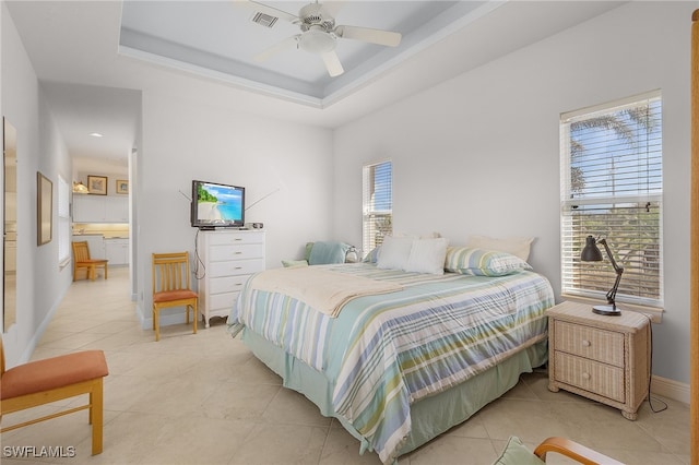 bedroom with a raised ceiling, multiple windows, ceiling fan, and light tile patterned flooring