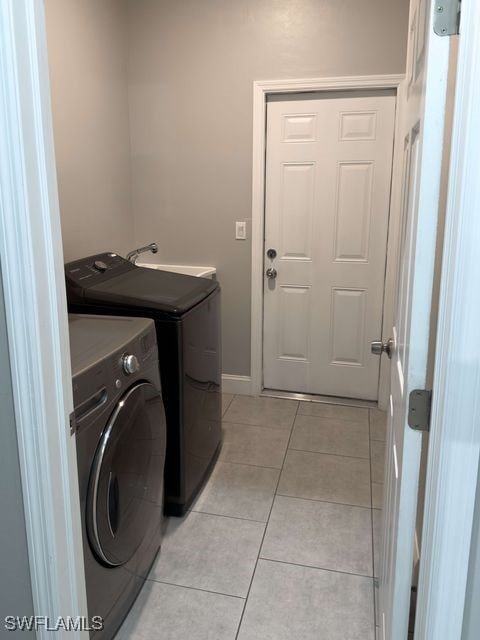 laundry area featuring light tile patterned flooring, separate washer and dryer, and sink