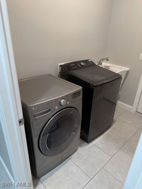 clothes washing area with light tile patterned floors and washer and dryer