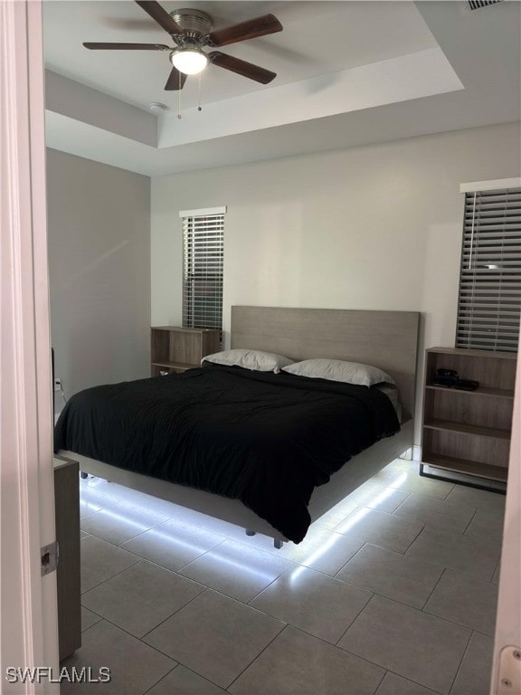 bedroom featuring a raised ceiling and ceiling fan