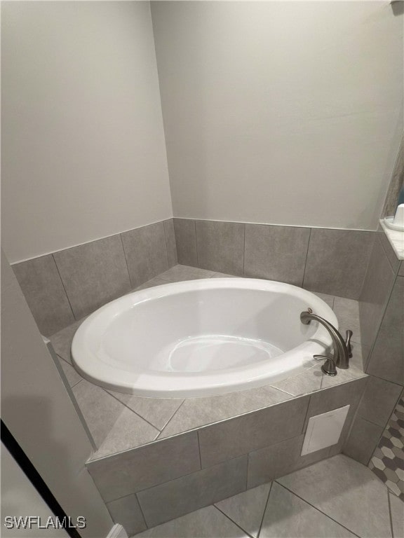 bathroom with tile patterned floors and tiled bath