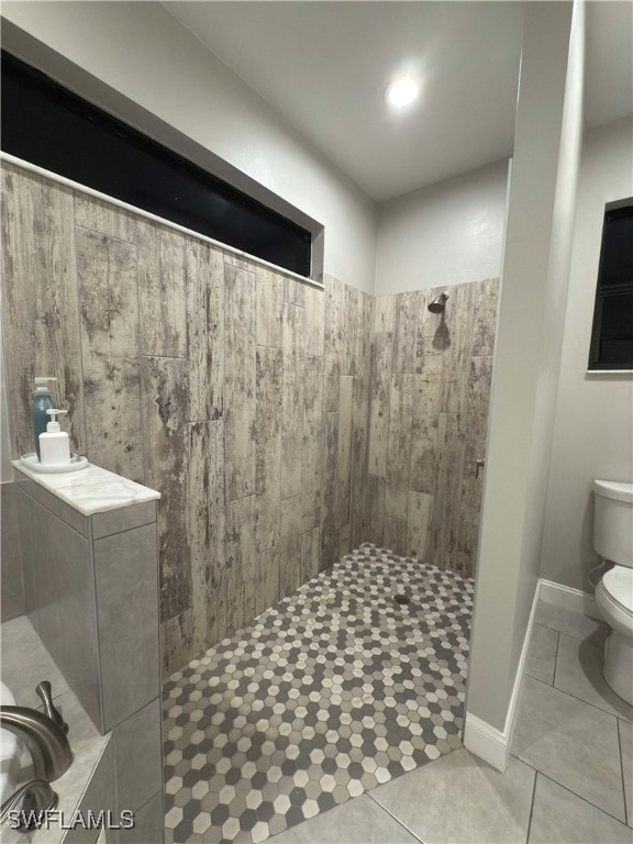 bathroom featuring tile patterned flooring, toilet, and tiled shower