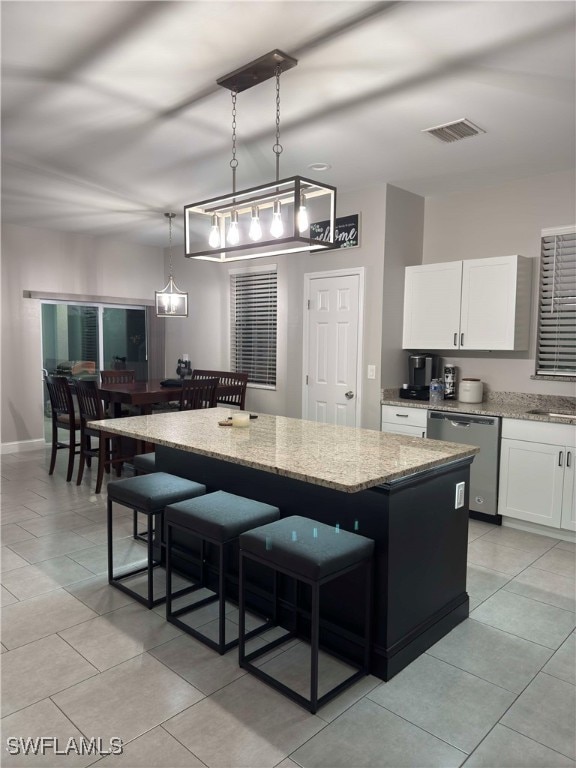 kitchen featuring stainless steel dishwasher, light stone counters, white cabinets, a center island, and hanging light fixtures