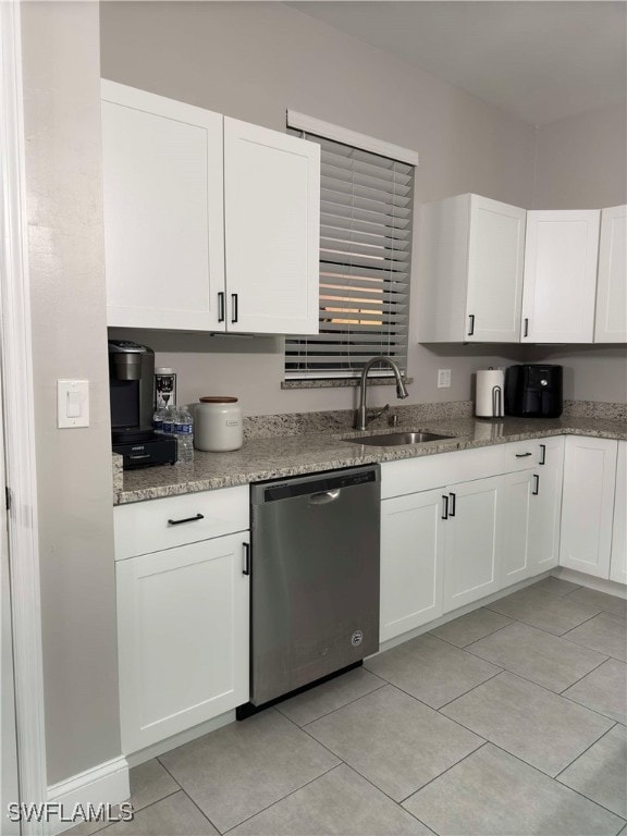 kitchen with stainless steel dishwasher, light tile patterned flooring, white cabinets, and sink