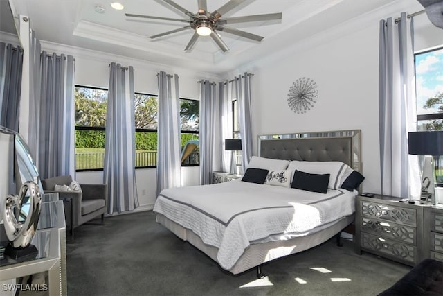 bedroom featuring a tray ceiling, multiple windows, ornamental molding, and ceiling fan