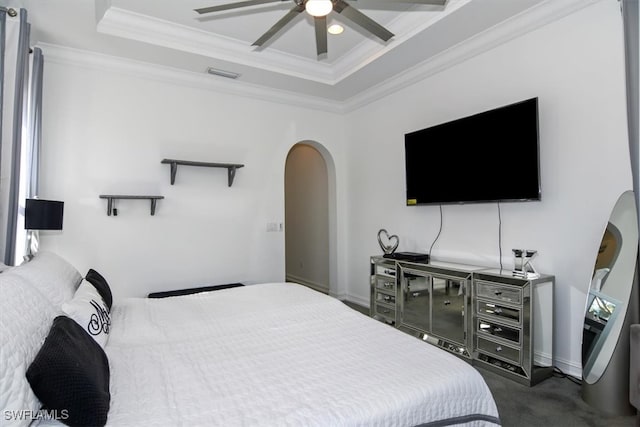 bedroom featuring a tray ceiling, ceiling fan, crown molding, and dark carpet