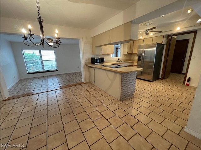 kitchen with sink, appliances with stainless steel finishes, light tile patterned flooring, ceiling fan with notable chandelier, and kitchen peninsula