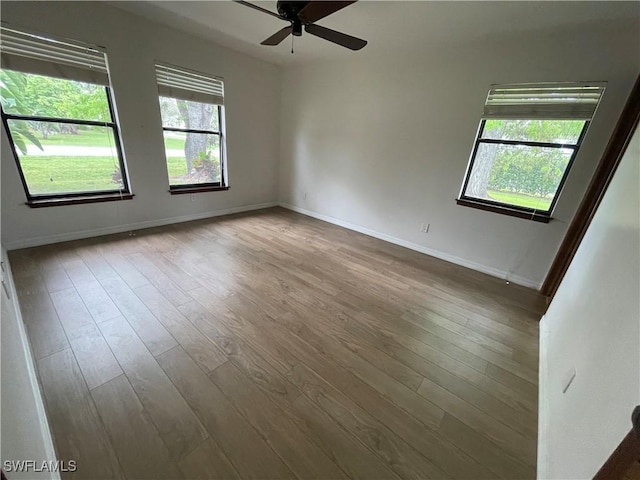 spare room featuring ceiling fan, a healthy amount of sunlight, and hardwood / wood-style floors