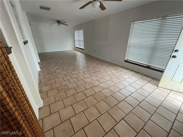 tiled empty room with a ceiling fan, visible vents, and baseboards