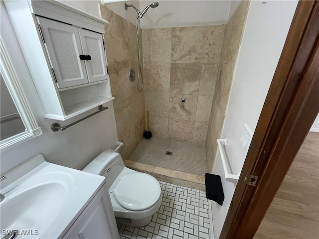 bathroom featuring tiled shower, vanity, and toilet