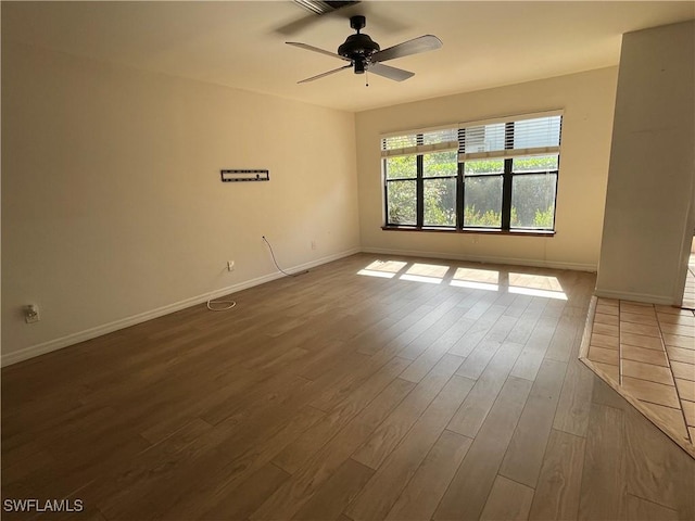 empty room with dark wood-style floors, ceiling fan, and baseboards