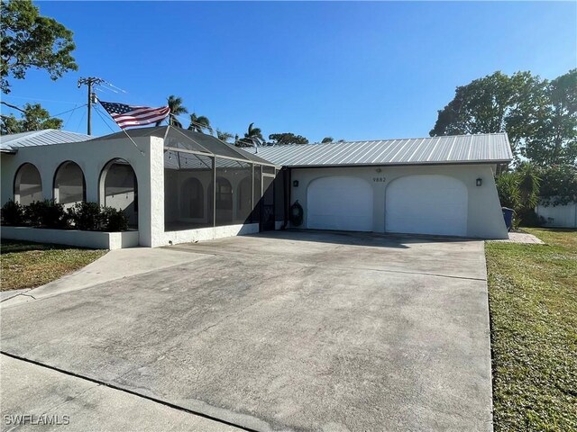 9882 Connecticut St, Bonita Springs, FL 34135 - view of front of home featuring an attached garage, driveway, metal roof, and stucco siding