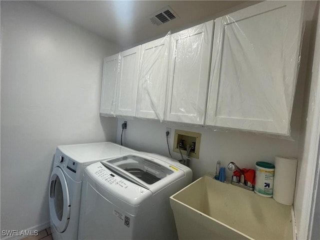 laundry area featuring washer and dryer, visible vents, cabinet space, and a sink