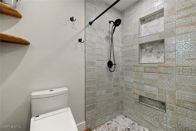 bathroom featuring toilet and a tile shower