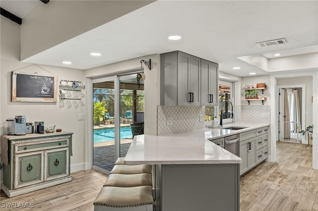 kitchen featuring a kitchen bar, kitchen peninsula, sink, and light wood-type flooring