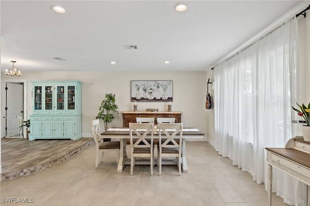 dining room with light hardwood / wood-style flooring and an inviting chandelier