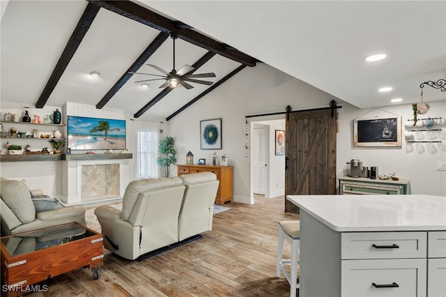 living room with lofted ceiling with beams, ceiling fan, a barn door, and light hardwood / wood-style floors