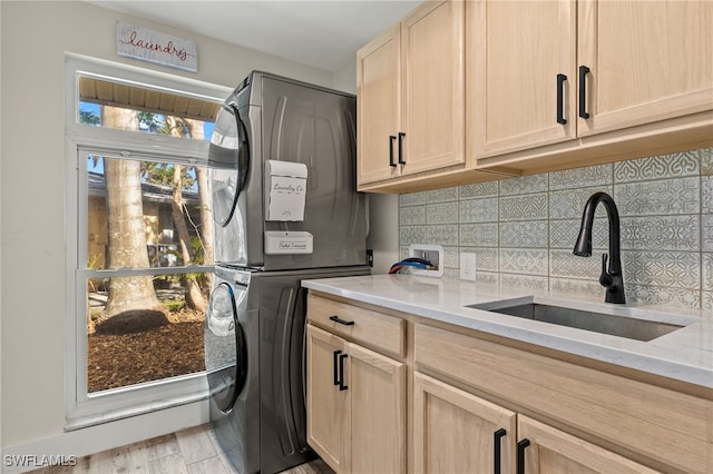 laundry room with light wood-type flooring, cabinets, stacked washer / drying machine, and sink