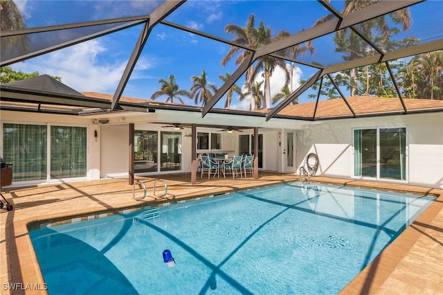 view of swimming pool with glass enclosure, a patio area, and ceiling fan