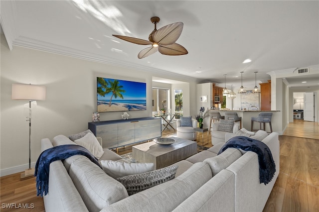 living room with crown molding, ceiling fan, and light wood-type flooring