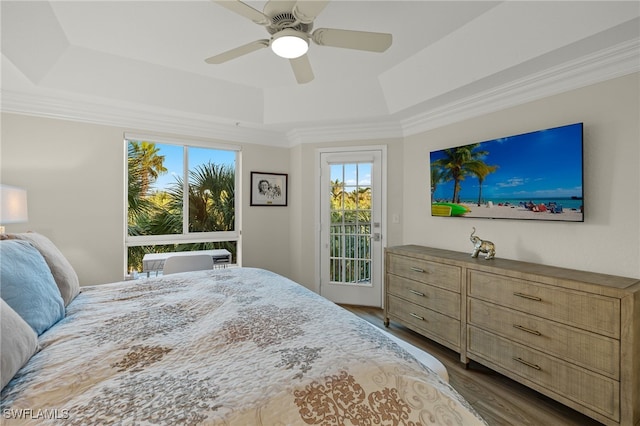 bedroom featuring ceiling fan, a raised ceiling, wood-type flooring, access to outside, and ornamental molding