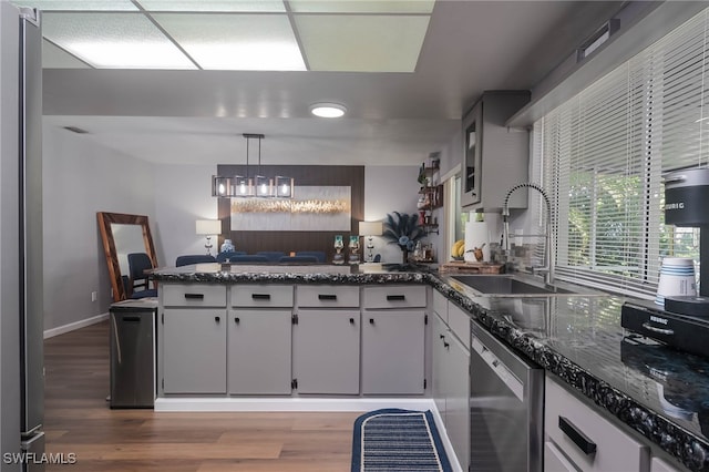 kitchen with hanging light fixtures, sink, white cabinets, and stainless steel dishwasher