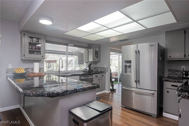 kitchen featuring kitchen peninsula, stainless steel appliances, white cabinetry, and hardwood / wood-style flooring