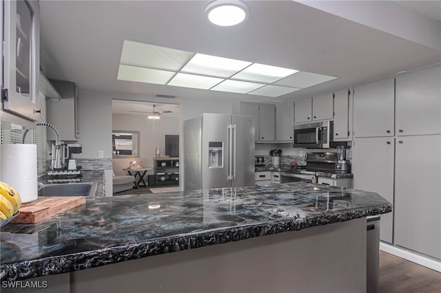 kitchen with kitchen peninsula, stainless steel appliances, dark hardwood / wood-style floors, and ceiling fan