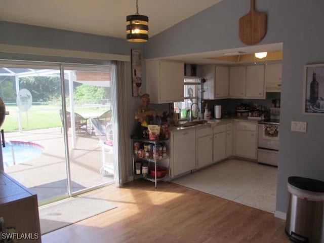 kitchen featuring white stove, hanging light fixtures, light hardwood / wood-style floors, and white cabinets