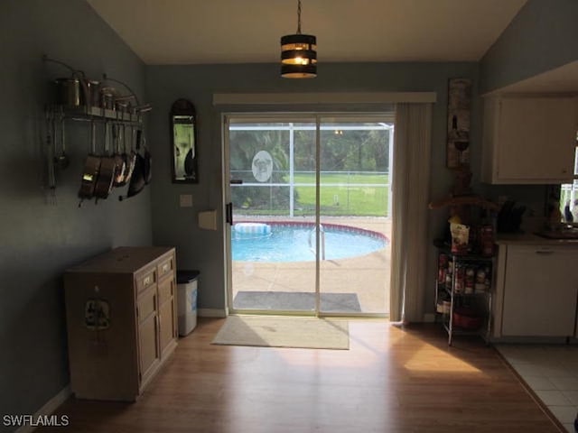 doorway to outside featuring vaulted ceiling and light hardwood / wood-style flooring