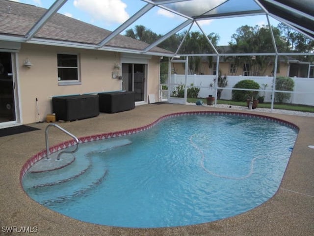 view of swimming pool with glass enclosure and a patio