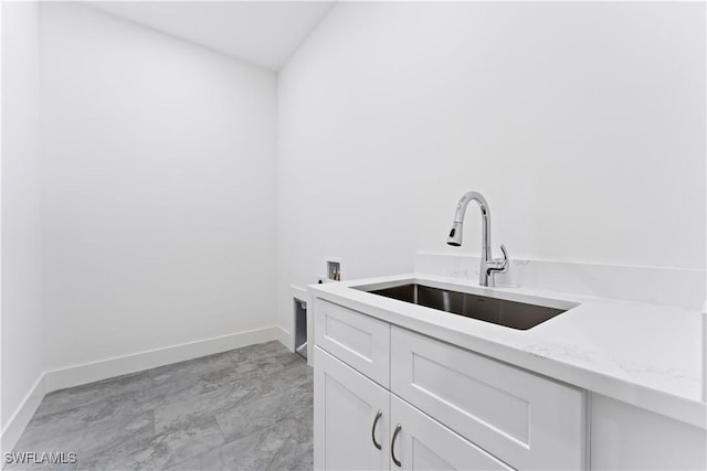 interior space featuring hookup for a washing machine, cabinet space, a sink, and baseboards