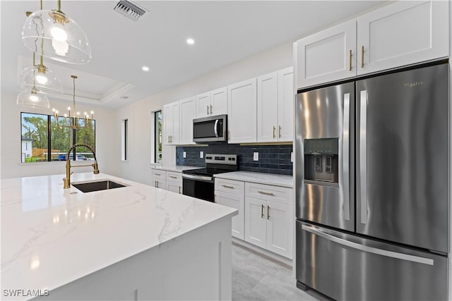 kitchen featuring stainless steel appliances, a tray ceiling, light stone counters, and white cabinets