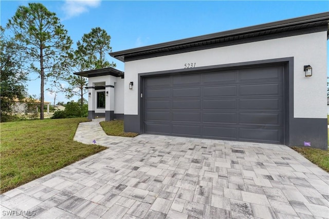 view of front facade featuring decorative driveway, an attached garage, a front lawn, and stucco siding