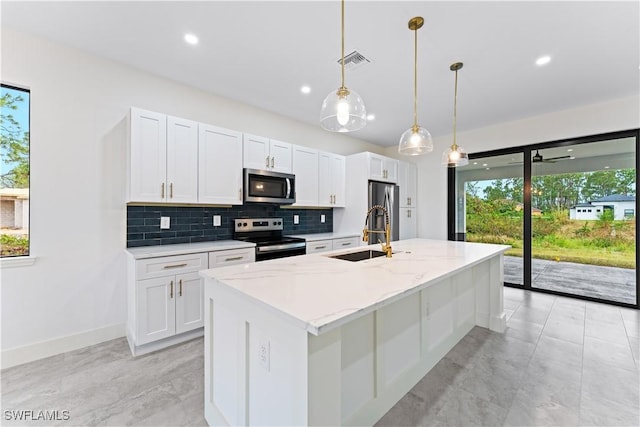 kitchen featuring appliances with stainless steel finishes, a sink, a center island with sink, and white cabinets