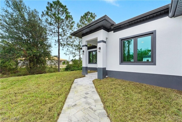 doorway to property with a lawn and stucco siding