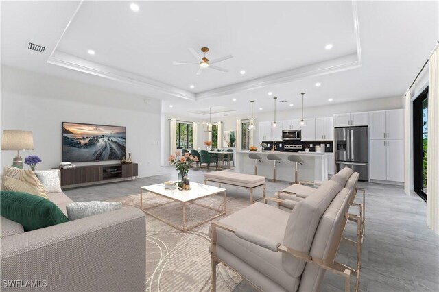 living room featuring ceiling fan and a tray ceiling