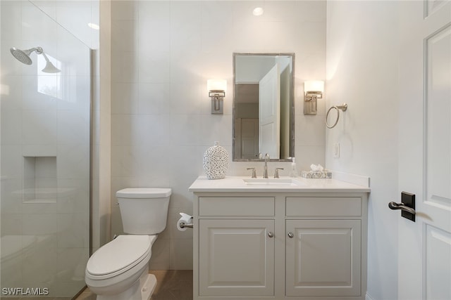 bathroom featuring walk in shower, vanity, toilet, and tile walls