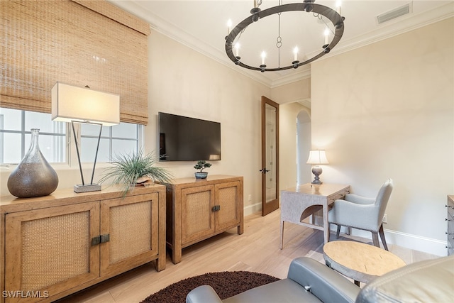 living room featuring light wood-type flooring, a notable chandelier, and crown molding