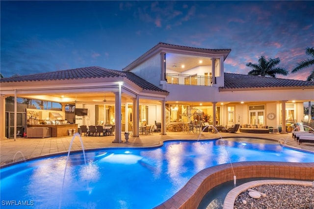 pool at dusk with outdoor lounge area, pool water feature, and a patio