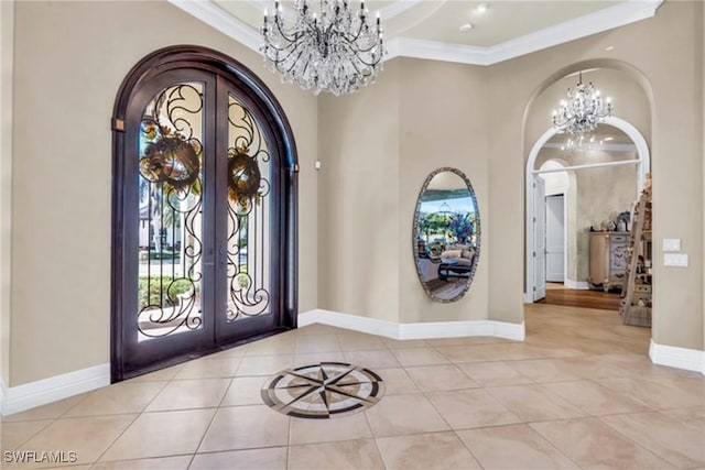 foyer entrance featuring a chandelier, ornamental molding, light tile patterned floors, and french doors