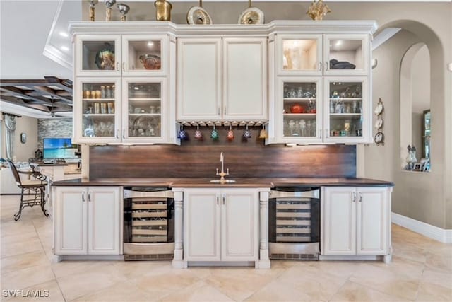 bar with white cabinetry, sink, beverage cooler, and ornamental molding