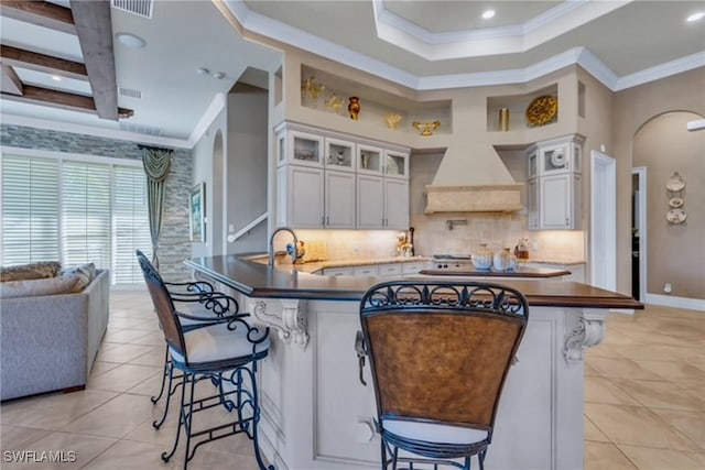 kitchen with a breakfast bar, white cabinetry, backsplash, and light tile patterned floors