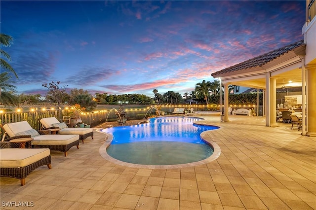 pool at dusk featuring pool water feature and a patio area